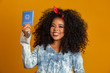 © Brastock Images - Beautiful curly-haired girl holding a work card. On yellow background.