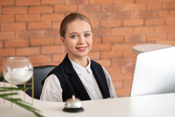 Poster - Young female receptionist at desk in hotel