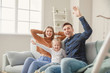 © Pixel-Shot - Happy young family sitting on sofa at home