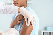 Doctor Vaccinating Teenage Boy In Clinic, Closeup