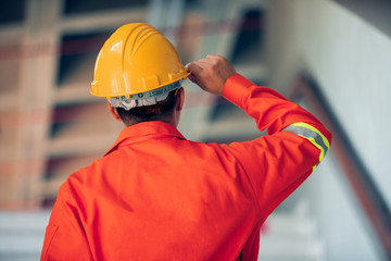 The back view of Engineers wear helmets and uniforms, working on construction sites, Asian workers and building structures.