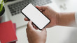 © bongkarn - Cropped shot of businessman holding smartphone in workspace with other office supplies on blurred white table