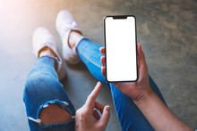 Mockup Image Of A Woman Holding Black Mobile Phone With Blank White Screen While Sitting On The Floor