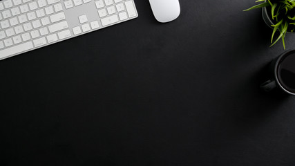 Overhead shot of dark modern workspace with computer keyboard, coffee cup and copy space