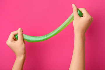 Woman playing with green slime on pink background, closeup. Antistress toy