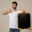 © SB Arts Media - Stylish handsome man showing suitcase. Advertising storage space for travelers and tourism image.