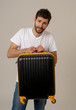 © SB Arts Media - Stylish handsome man showing suitcase. Advertising storage space for travelers and tourism image.