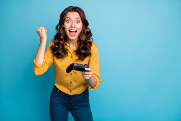 Portrait of her she nice attractive lovely overjoyed cheerful cheery wavy-haired girl playing video game win winner isolated on bight vivid shine vibrant green blue turquoise color background