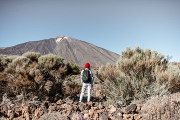 Wall Mural - Young woman in red hat traveling with backpack on the volcano valley, hiking on a Teide national park on Tenerife island