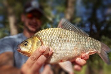 Wall Mural - Young happy angler holds the fish