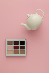 Wall Mural - White teapot and makeup shadows on a pink background. Concept - daily trend makeup as a routine