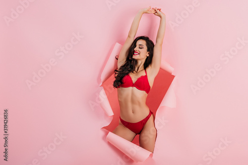 Cuadros en Lienzo sexy, smiling girl in red lingerie standing with raised hands in paper hole on p