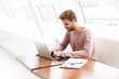 © Drobot Dean - Image of young man wearing earbuds working on laptop in cafe indoors