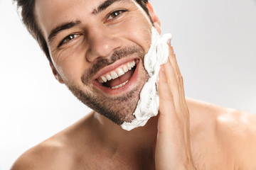 Wall Mural - Photo of cheerful half-naked man applying shaving foam and smiling