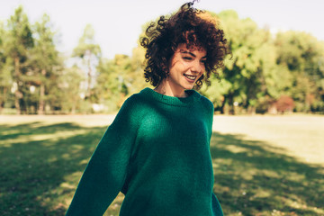 beautiful young woman smiling posing against nature background with windy curly hair, have positive 