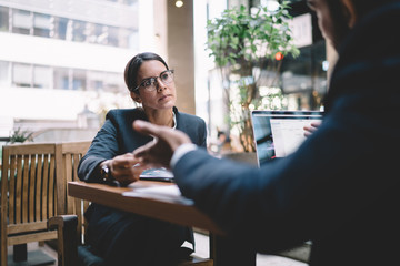 Careful businesswoman listening to colleague at workplace