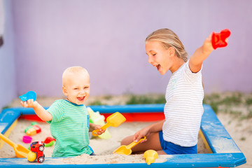 Sticker - Cute baby boy playing with his sister in the sandbox