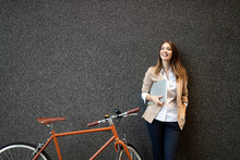 Young Businesswoman Standing On A City Street With Bicycle