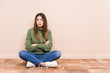 Young caucasian woman sitting on the floor isolated unhappy looking in camera with sarcastic expression.