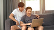 © witthaya - Gay couple using laptop in living room