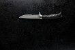 Closeup of a sharpened cool military combat knife on a grungy black background