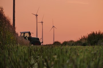 Sticker - Beautiful shot of a tractor working in the fields with wind power plants in the background