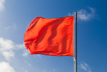 Red Warning Flag On A Beach Waving On Strong Wind