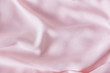 Pink wrinkled silk fabric. The pink fabric is laid out waves. Pink fabric background or texture.
