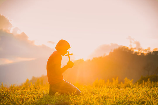 The silhouette of a woman's hand with the symbol of the cross on the sunset background, the cross, symbol of faith It is a belief in Christian concepts.