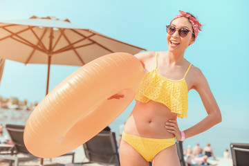 Wall Mural - Happy Asian girl with an inflatable circle is resting and swimming at a popular seaside resort. Vacation and tan concept