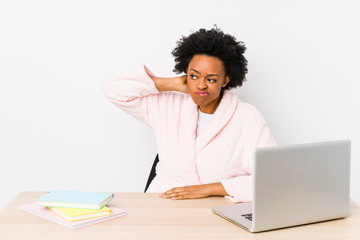 Middle aged african american woman working at home isolated touching back of head, thinking and making a choice.