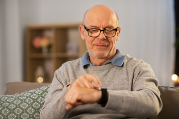 Sticker - time, morning and people concept - senior man looking at wristwatch at home in evening