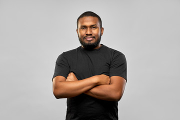 people concept - young african american man in black t-shirt with crossed arms over grey background