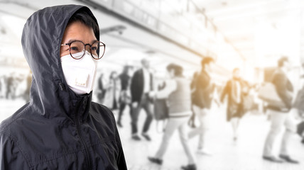 Asian man wearing surgical mask to prevent flu disease Corona virus and PM 2.5 dust with blurred image of crowded