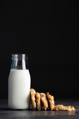 The cranberry cookies are placed in a black background with the milk in the bottle.