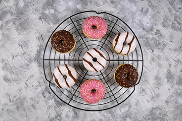 Wall Mural - Tasty donuts with different white and brown chocolate and strawberry glazings with sprinkles on cake grid 