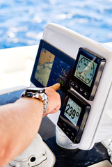 Close up male hand pointing on navigation devices in catamaran deck, adventure recreational sport, yachting concept