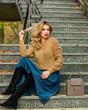 wait for him. female beauty. Fashion model. girl in corrugated skirt and sweater. Pleated trend. casual style student. fall season. autumn woman curly hair outdoor. girl long blond hair stairs