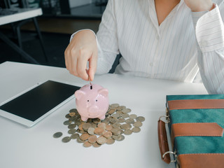 piggybank and business women working and calculate expenses with calculator and laptop. stak of coins. saving for investment and furure concept