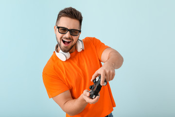 Sticker - Young man playing video game on color background