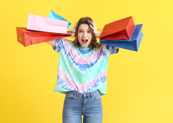 Wall Mural - Stressed female stylist with shopping bags on color background