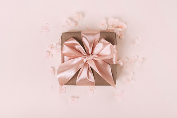 Wall Mural - Gift box wrapped in craft paper with perfect pink ribbon on pale pink rustic background.