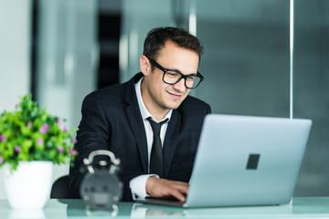 Wall Mural - Handsome young business man in suit in office with laptop.