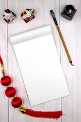 Wall Mural - Blank notepad page and art supplies. Oriental decor composition top view with text place. Empty notebook for Lunar New Year greeting