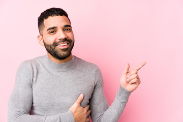 Wall Mural - Young latin man against a pink background isolated smiling cheerfully pointing with forefinger away.