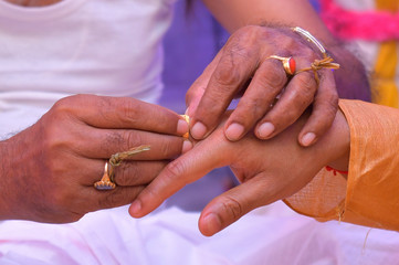 Colourful traditional view of bengali wedding rituals while grrom is wearing gold made ring in india