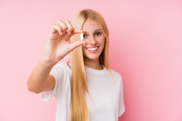 Young blonde woman taking some pills isolated on a blackground