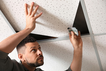 Wall Mural - Man hiding money under ceiling cell indoors. Financial savings