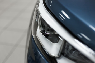 Wall Mural - Close-up headlights of a modern blue color car. Detail on the front light of a car. Modern and expensive car concept. The car is in the showroom. Automotive concept. Classic blue color