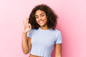 Wall Mural - Young african american woman against a pink background cheerful and confident showing ok gesture.